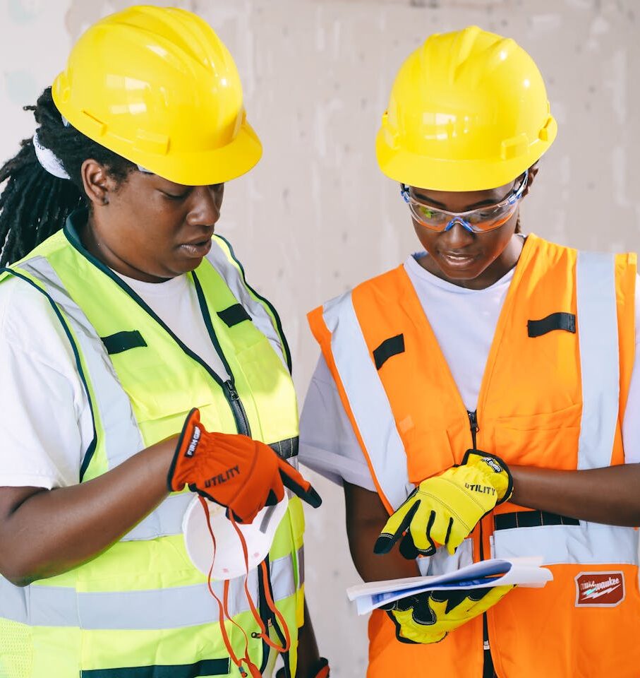 Two engineers in safety gear review construction plans, showcasing teamwork and safety.